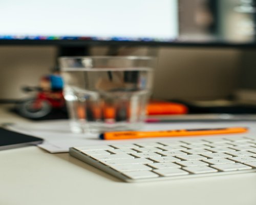 glass of water next to a keyboard on a desk